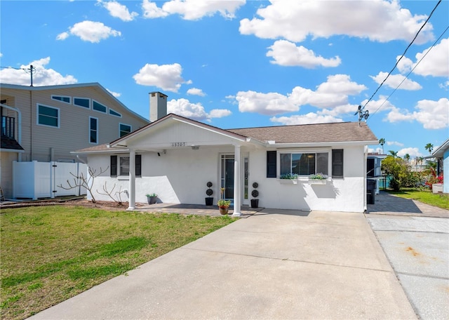 view of front of house with stucco siding, a front lawn, and fence