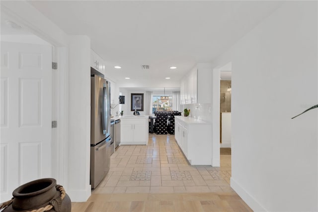 kitchen featuring decorative backsplash, white cabinets, appliances with stainless steel finishes, and light countertops