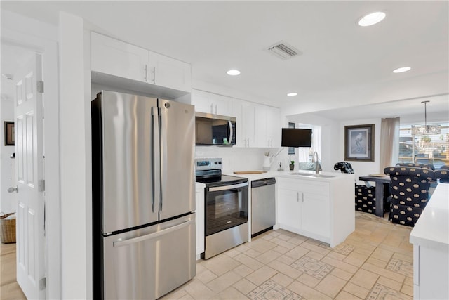 kitchen featuring visible vents, a sink, appliances with stainless steel finishes, white cabinets, and light countertops