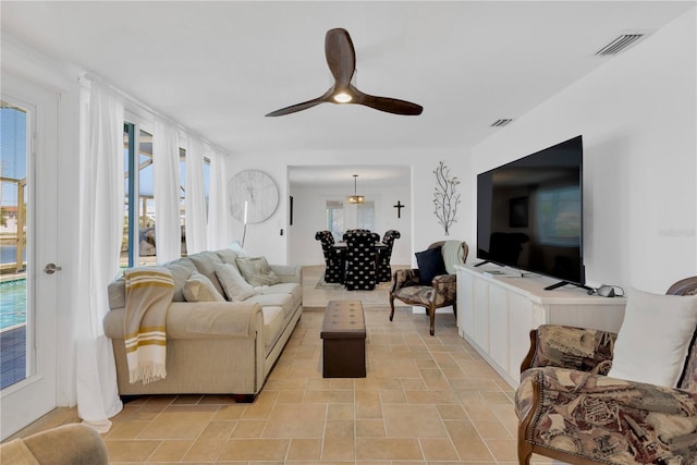 living area featuring visible vents, a healthy amount of sunlight, and ceiling fan