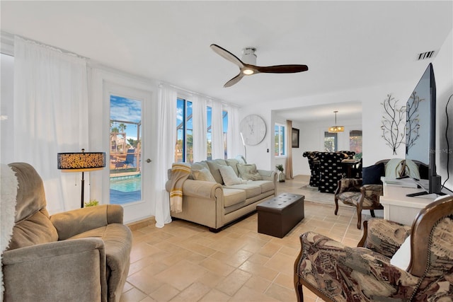 living area featuring stone tile flooring, visible vents, and a ceiling fan