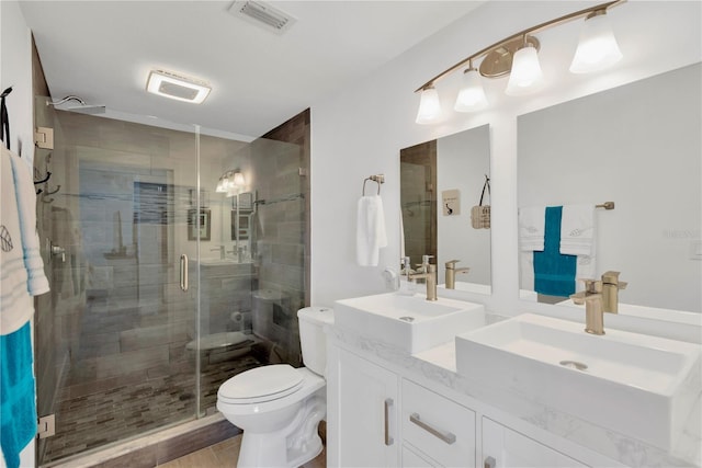 bathroom featuring a sink, visible vents, toilet, and a shower stall