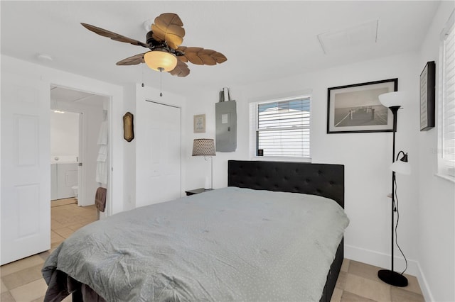 bedroom with ceiling fan, baseboards, attic access, electric panel, and ensuite bath