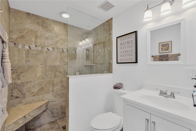 bathroom with visible vents, toilet, a walk in shower, and vanity