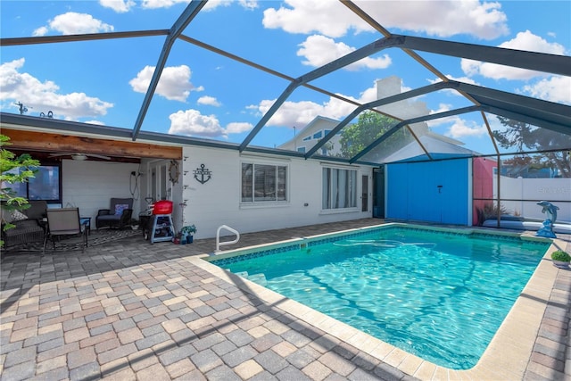 outdoor pool featuring an outbuilding, a shed, ceiling fan, a lanai, and a patio area