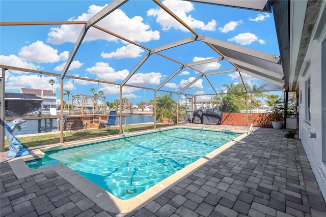 outdoor pool with grilling area, a water view, a lanai, and a patio area