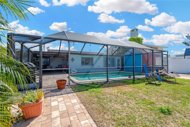 back of property with fence, a patio area, an outdoor pool, and a lawn