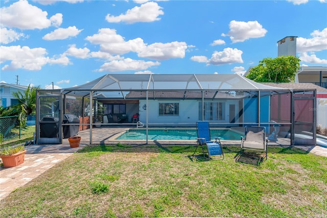 back of property with an outdoor pool, glass enclosure, a patio, and a lawn