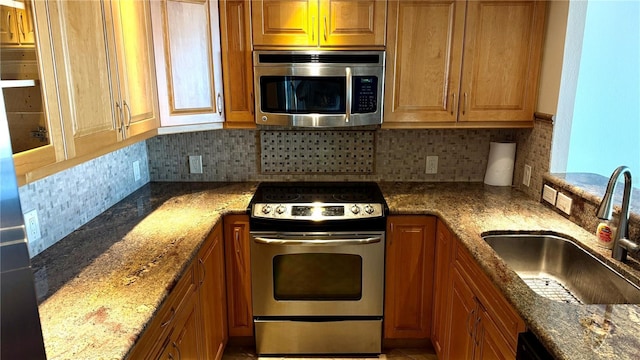 kitchen with brown cabinetry, stainless steel appliances, and a sink