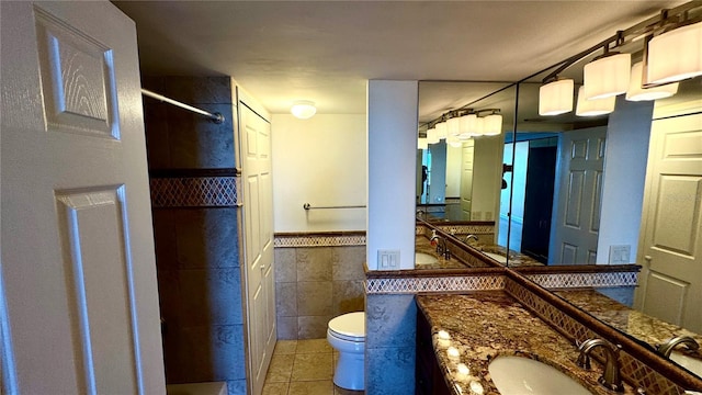 bathroom with toilet, tile walls, a shower, wainscoting, and tile patterned floors