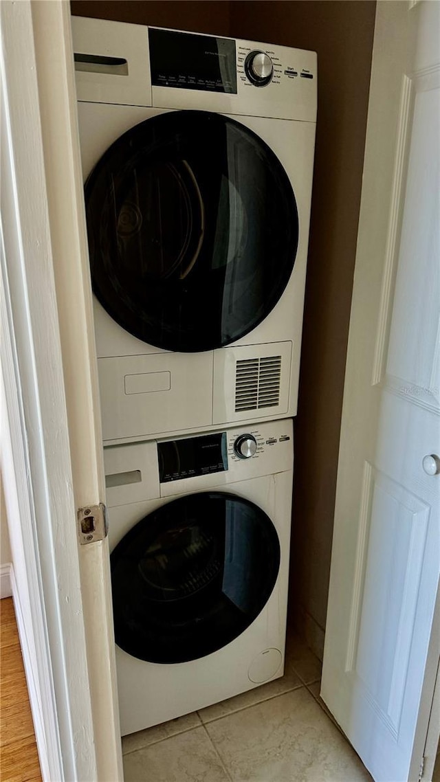 washroom featuring light tile patterned floors, stacked washer and dryer, and laundry area