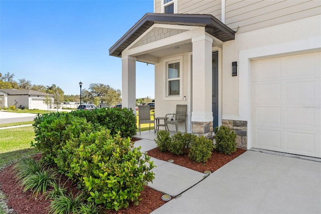 doorway to property featuring stone siding, covered porch, and stucco siding