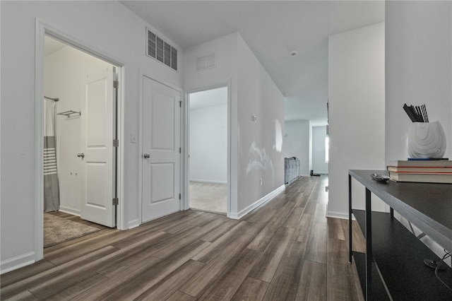 corridor featuring baseboards, visible vents, and wood finished floors