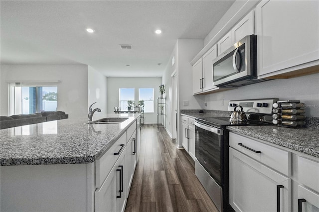 kitchen with appliances with stainless steel finishes, dark wood-type flooring, white cabinetry, a sink, and an island with sink