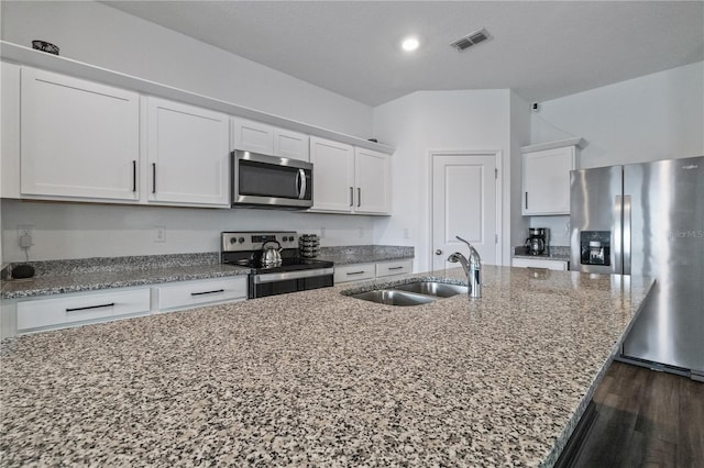 kitchen with a center island with sink, visible vents, appliances with stainless steel finishes, white cabinets, and a sink