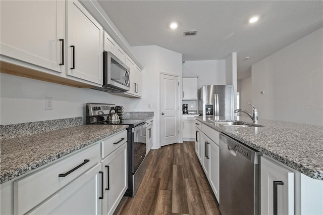 kitchen featuring stone countertops, visible vents, stainless steel appliances, white cabinetry, and a sink