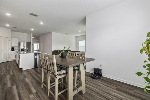 dining area featuring dark wood-type flooring, a healthy amount of sunlight, and visible vents