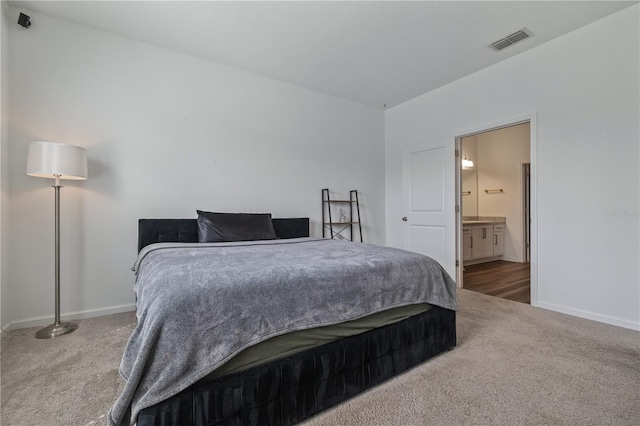 carpeted bedroom featuring visible vents, ensuite bath, and baseboards