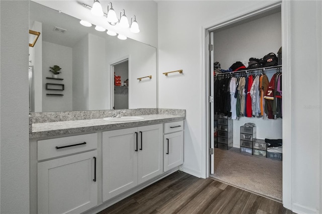 bathroom featuring visible vents, a spacious closet, wood finished floors, and vanity