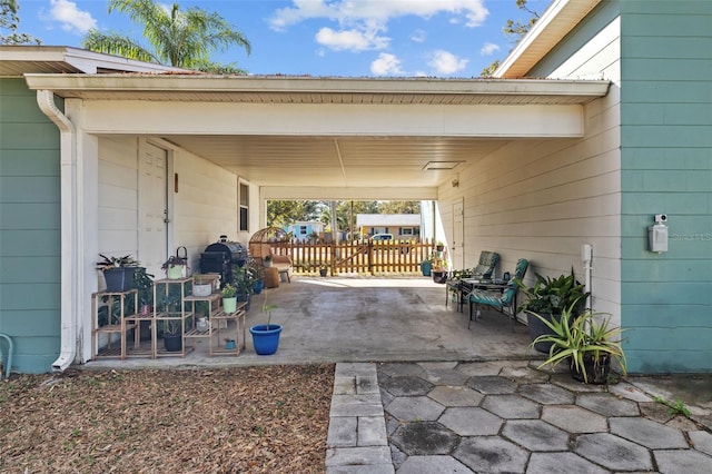 view of patio with an attached carport and fence