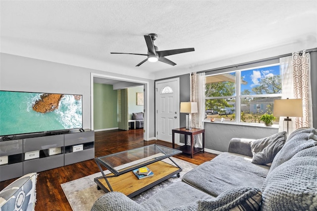 living room featuring a textured ceiling, a ceiling fan, baseboards, and wood finished floors