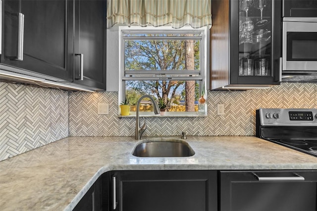 kitchen featuring a sink, appliances with stainless steel finishes, dark cabinetry, and light countertops