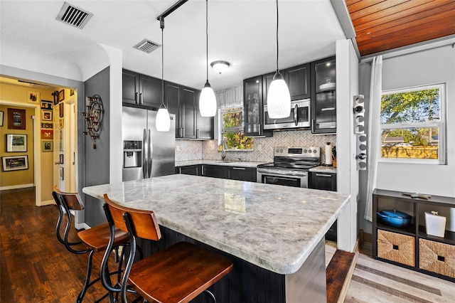 kitchen featuring tasteful backsplash, visible vents, stainless steel appliances, and a breakfast bar