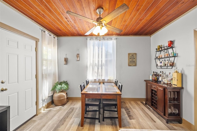 dining room with a bar, light wood-style flooring, wood ceiling, and ornamental molding