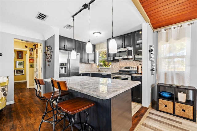 kitchen with tasteful backsplash, visible vents, light stone counters, appliances with stainless steel finishes, and a kitchen breakfast bar