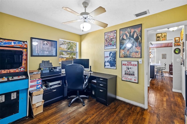 office area featuring dark wood finished floors, baseboards, visible vents, and ceiling fan