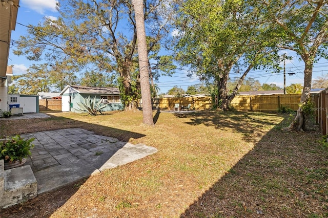 view of yard featuring a patio, an outbuilding, and a fenced backyard