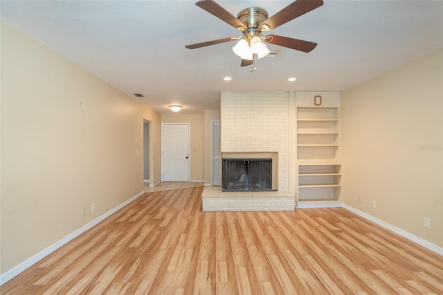 unfurnished living room featuring a fireplace, visible vents, baseboards, light wood-style floors, and built in features