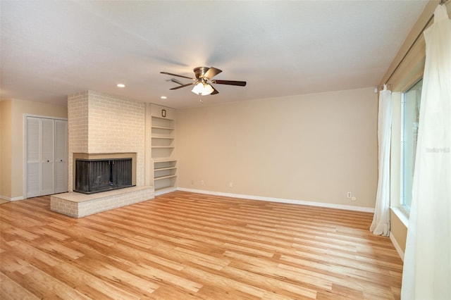 unfurnished living room featuring baseboards, light wood finished floors, a fireplace, and built in features