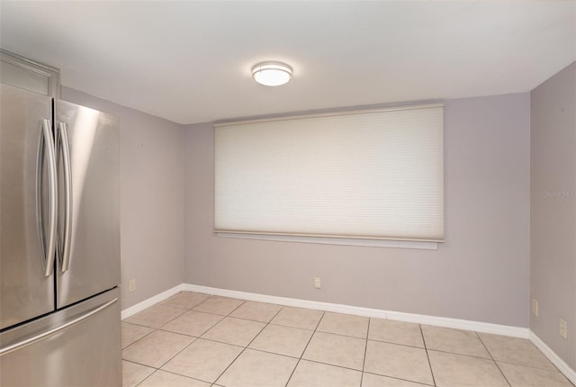 empty room with baseboards and light tile patterned flooring