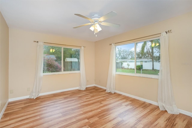 empty room with light wood-type flooring, a ceiling fan, and baseboards