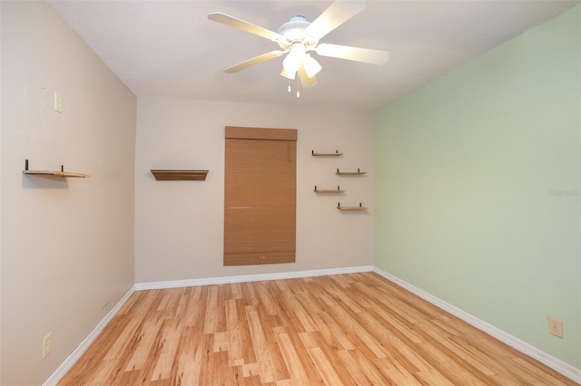 empty room featuring light wood finished floors, baseboards, and a ceiling fan