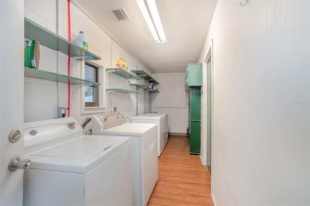 laundry area featuring laundry area, visible vents, light wood finished floors, and washing machine and clothes dryer