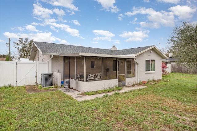 rear view of house with a lawn, a sunroom, a gate, cooling unit, and a fenced backyard