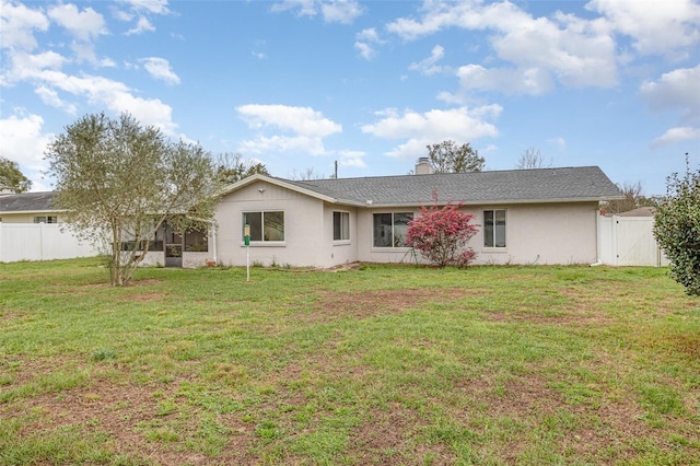 back of property featuring a lawn, a chimney, a gate, fence, and stucco siding