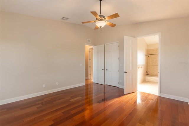 unfurnished bedroom featuring ensuite bath, ceiling fan, vaulted ceiling, and dark wood-type flooring