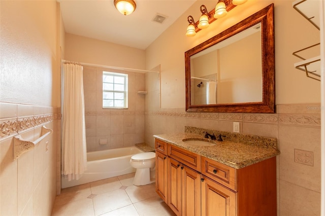 full bathroom with shower / bath combo with shower curtain, tile walls, vanity, toilet, and tile patterned floors