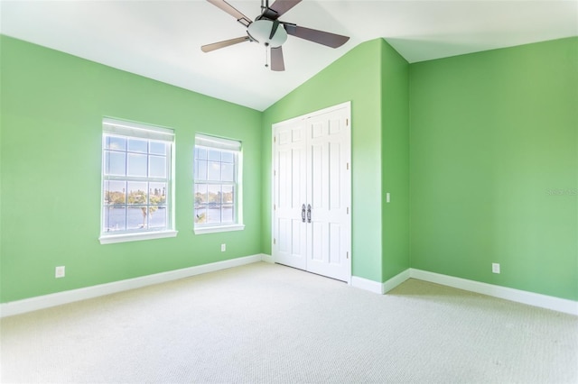 unfurnished bedroom with light carpet, a closet, ceiling fan, and vaulted ceiling