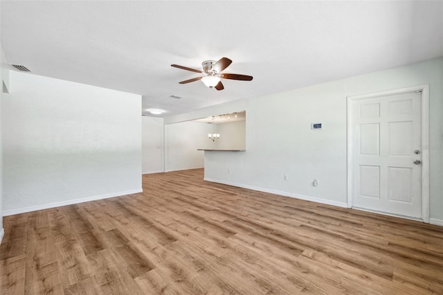 1119 77th St N, Saint Petersburg, FL 33710 - unfurnished living room with light wood-style floors, ceiling fan with notable chandelier, visible vents, and baseboards