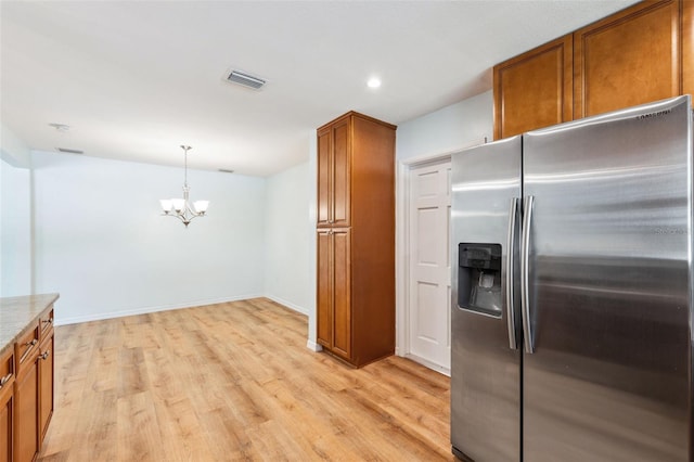 1119 77th St N, Saint Petersburg, FL 33710 - kitchen featuring visible vents, brown cabinets, light wood-style floors, a notable chandelier, and stainless steel fridge