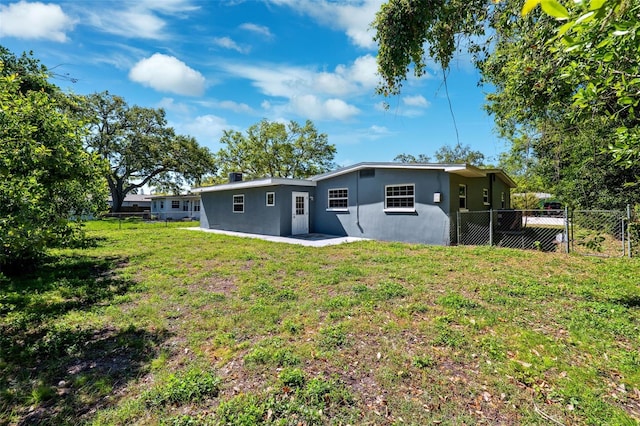 1119 77th St N, Saint Petersburg, FL 33710 - rear view of house with a lawn, fence, and stucco siding