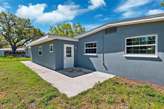 1119 77th St N, Saint Petersburg, FL 33710 - view of exterior entry with a patio, fence, a lawn, and stucco siding