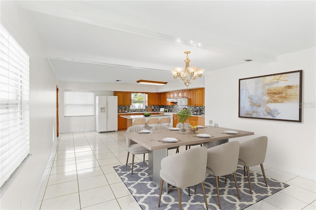 dining space featuring beamed ceiling, an inviting chandelier, and light tile patterned floors