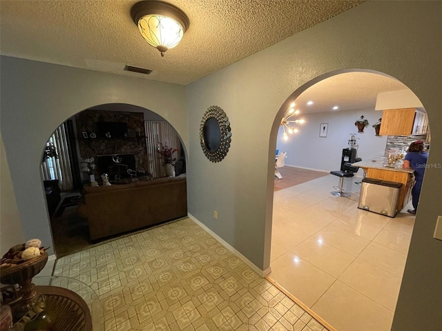 hall featuring light tile patterned flooring and a textured ceiling