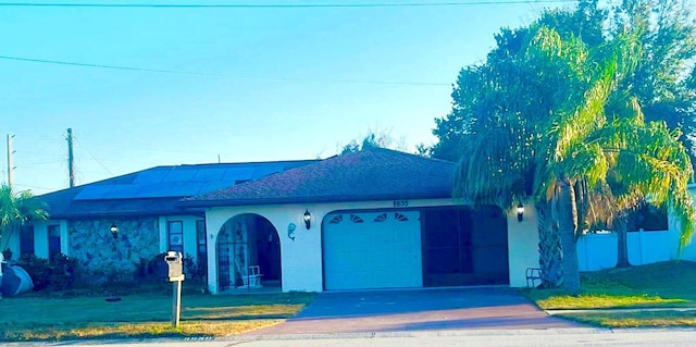 8630 Winter Haven Dr, Hudson, FL 34667 - view of front facade featuring an attached garage, concrete driveway, stucco siding, roof mounted solar panels, and roof with shingles