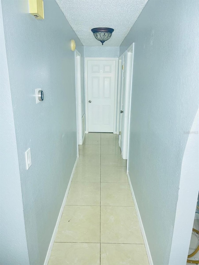 8630 Winter Haven Dr, Hudson, FL 34667 - hall featuring baseboards, a textured ceiling, light tile patterned floors, and a textured wall